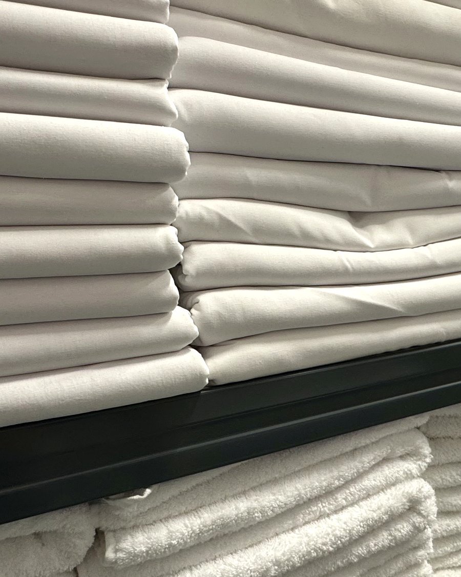 Piles de draps et serviettes propres, pliés et rangés — blanchisserie professionnelle Atelier du Linge